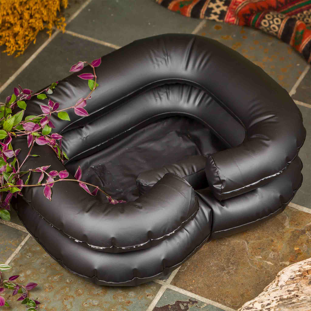Black inflatable basin float on a stone patio with plants