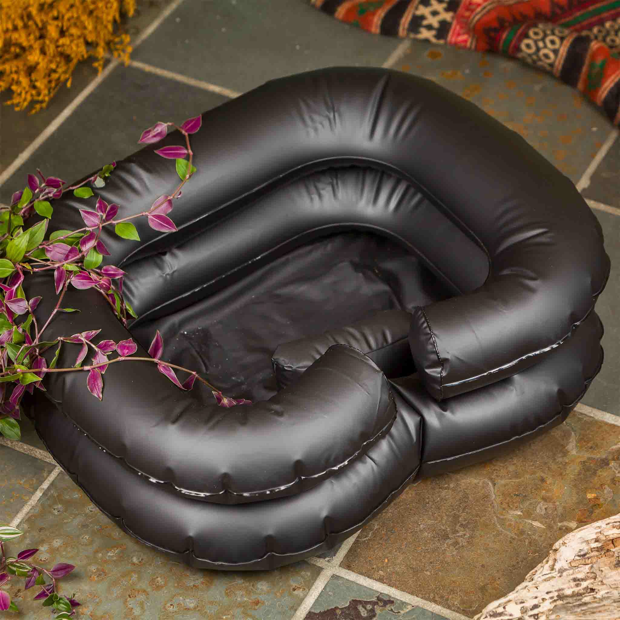 Black inflatable basin float on a stone patio with plants